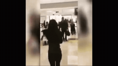 Woman In Hallway With People Walking GIF