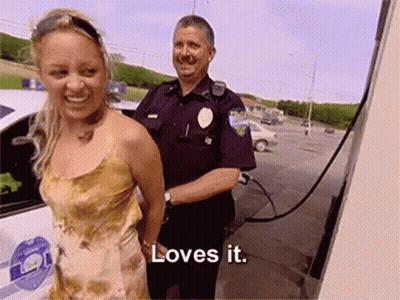 Woman In Handcuffs Smiling Next To Police Officer Saying Loves It GIF