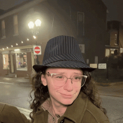 Woman In Hat And Glasses Smiling In Front Of No Parking Sign GIF