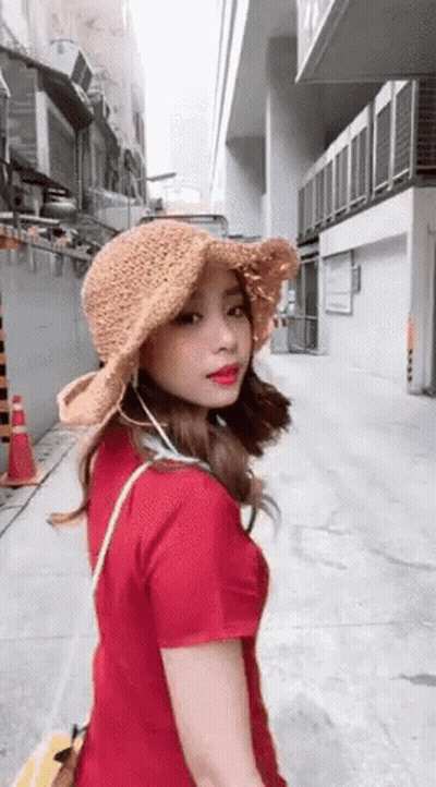 Woman In Hat And Red Shirt Walking Down Street GIF
