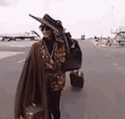 Woman In Hat And Sunglasses Carrying Suitcase GIF