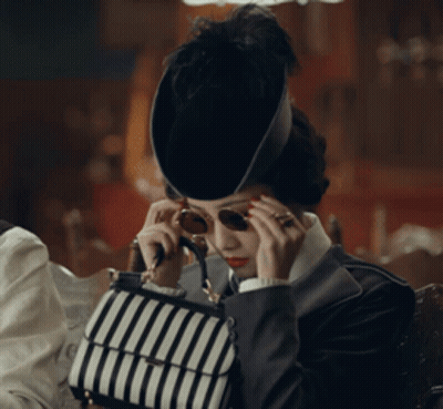 Woman in Hat and Sunglasses Holding Striped Bag