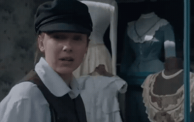 Woman In Hat And Vest In Front Of Window With Mannequins GIF