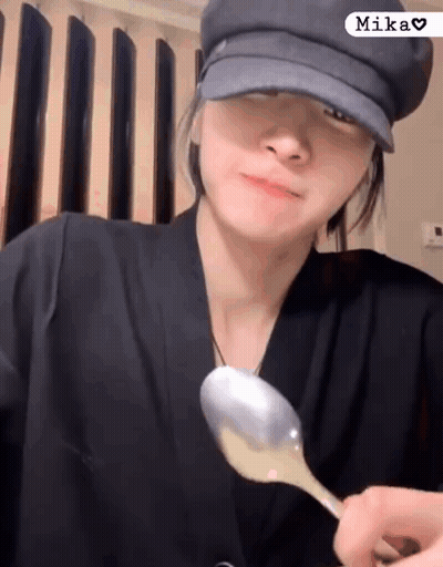 Woman In Hat Holding Spoon In Front Of Face GIF