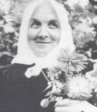 Woman In Head Scarf Holding Flowers And Smiling GIF