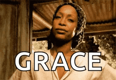 Woman In Head Scarf Standing In Front Of Grace Sign GIF