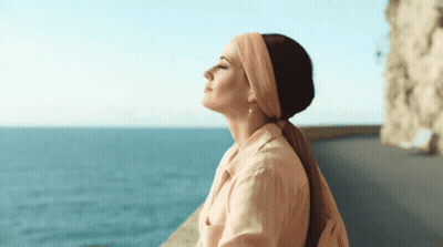 Woman In Headband And Earrings Overlooking Ocean GIF