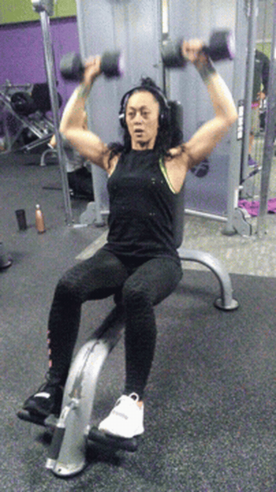 Woman In Headphones Lifting Dumbbells On Bench GIF
