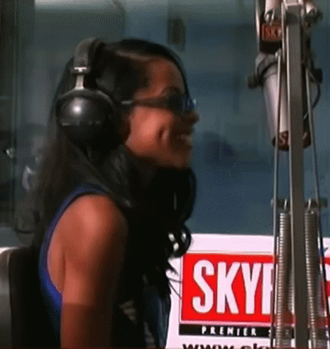 Woman In Headphones Smiling In Front Of Sky Sign GIF