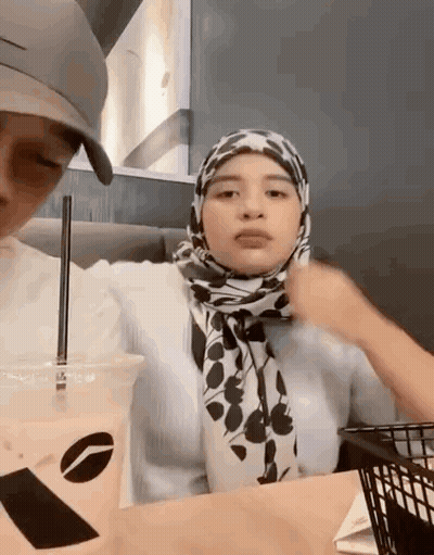 Woman In Hijab Sitting At Table With Coffee And Food Basket GIF