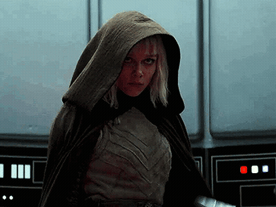 Woman In Hooded Cape Standing By Wall GIF