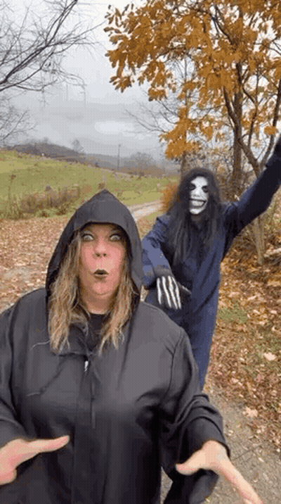 Woman In Hooded Jacket Next To Man In Mask GIF