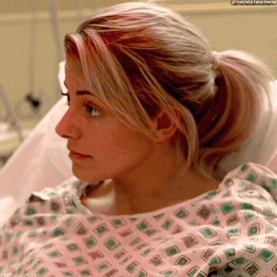 Woman In Hospital Gown With Ponytail Looking At Something GIF
