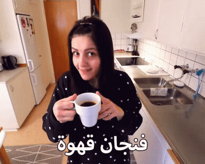 Woman In Kitchen Holding Coffee Cup With Arabic Writing GIF