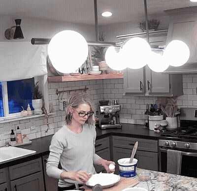 Woman In Kitchen Preparing Food With Yogurt Container GIF