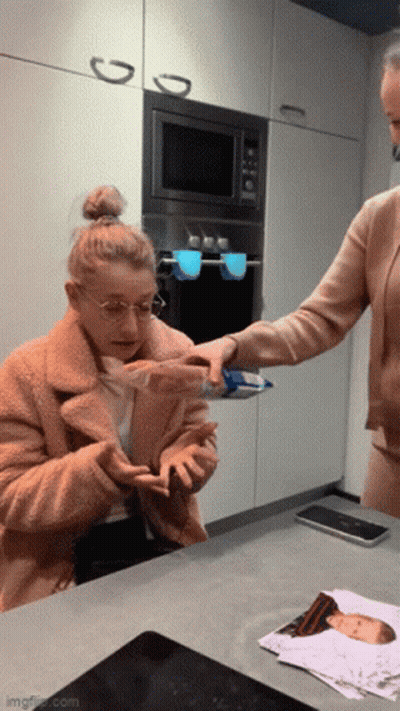 Woman In Kitchen With Baby Picture Behind GIF