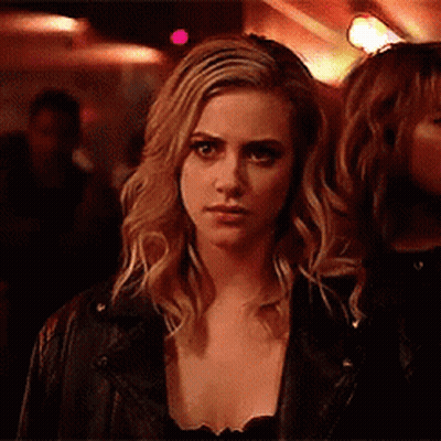Woman In Leather Jacket Looking At Camera In Dark Room GIF
