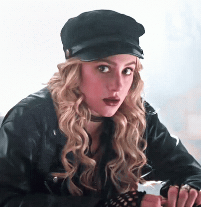 Woman In Leather Jacket Looking At Camera In Dark Room GIF