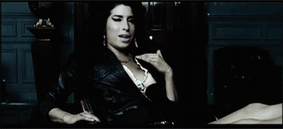 Woman In Leather Jacket Sitting By Statue GIF