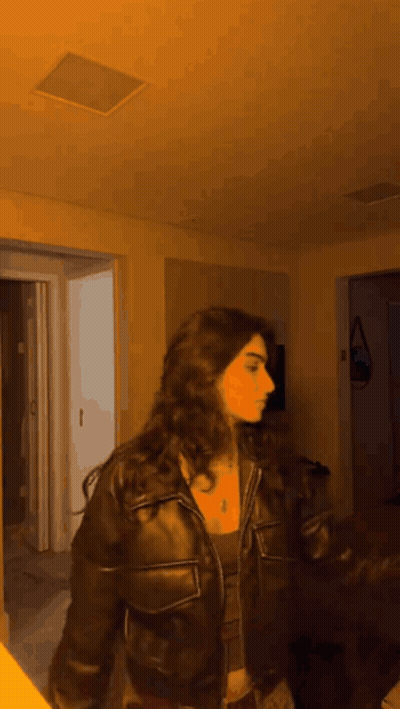 Woman In Leather Jacket Standing By Open Door GIF