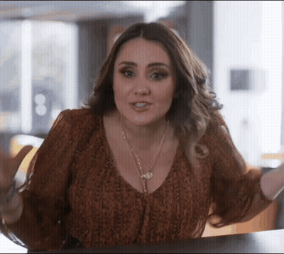 Woman In Leopard Print Top Sitting With Arms Outstretched GIF