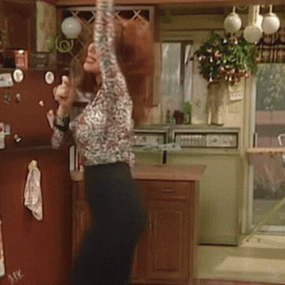 Woman In Leopard Shirt Arms Up In Kitchen GIF
