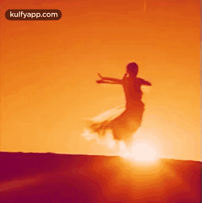 Woman In Long Dress Jumping At Sunset GIF