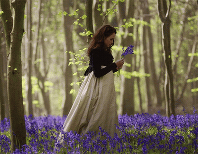 Woman In Long White Dress In Blue Flower Field GIF