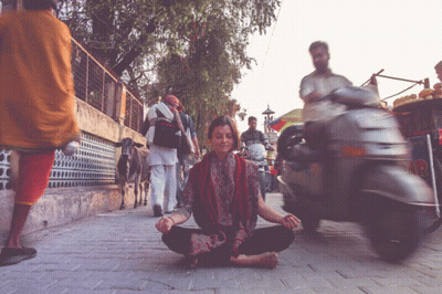 Woman In Lotus Position On Busy Street With Scooter GIF