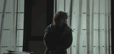 Woman In Mask In Dark Room By Window GIF