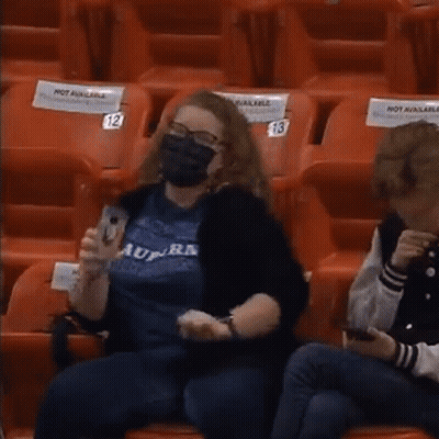 Woman In Mask Sitting In Empty Stadium With Not Available Sign GIF