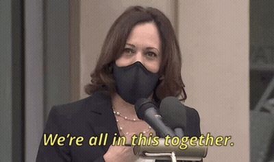 Woman in Mask Speaking Into Microphone Saying We're All in This Together