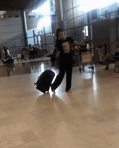 Woman In Nike T-Shirt Holding Suitcase At Airport GIF