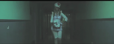 Woman In Nurse Costume Walking Down Hallway At Night GIF