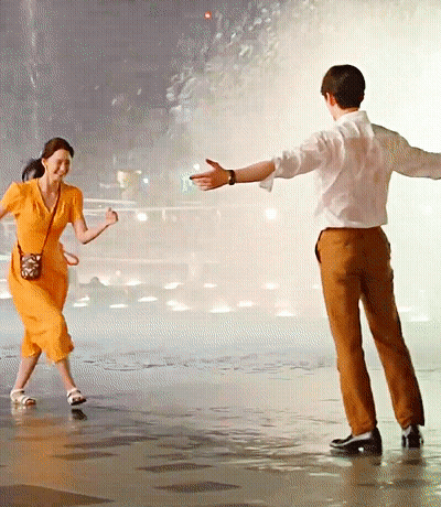 Woman In Orange Dress Dancing With Man In Brown Pants GIF