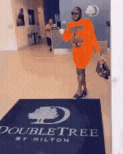 Woman In Orange Dress Walking Through Doubletree Lobby GIF
