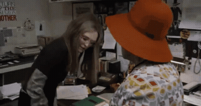 Woman In Orange Hat Talking In Office GIF