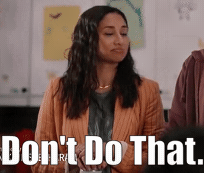 Woman In Orange Jacket Standing Before Do Not Do That Sign GIF