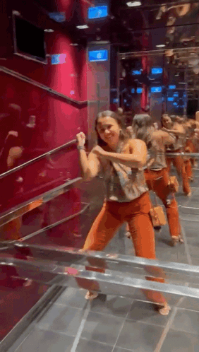 Woman In Orange Pants Dancing In Front Of Exit Sign GIF