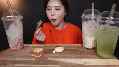 Woman In Orange Shirt Eating Sandwich GIF