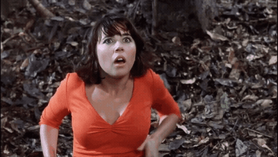 Woman In Orange Shirt Standing In Woods GIF