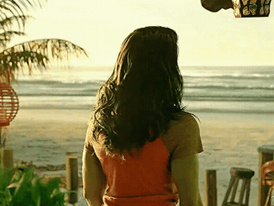 Woman In Orange Shirt Standing On Beach GIF