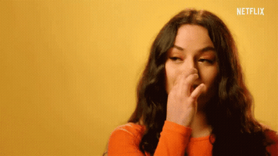 Woman In Orange Sweater Covering Nose GIF