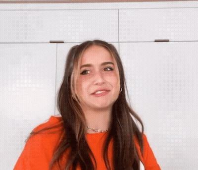 Woman In Orange Sweater Making Funny Face GIF