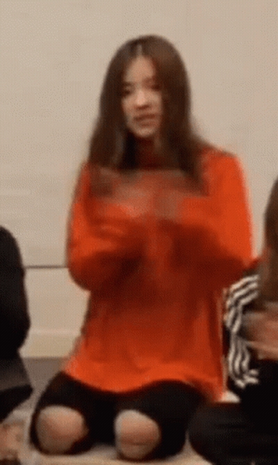 Woman In Orange Sweater Sitting GIF