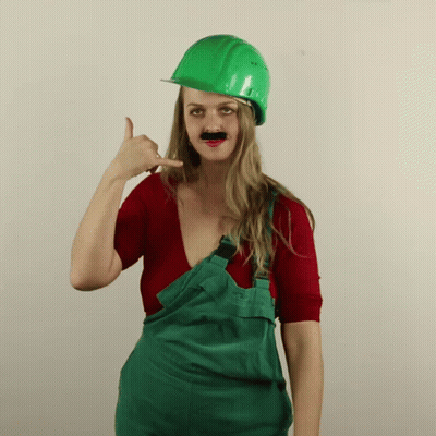 Woman In Overalls And Green Hard Hat Making Call Me Sign GIF