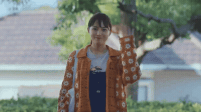 Woman In Overalls And Orange Jacket With Flowers GIF