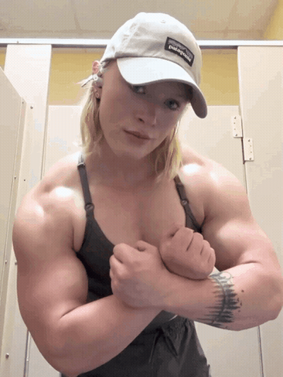 Woman In Patagonia Hat Flexing Muscles In Bathroom GIF