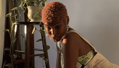 Woman In Pearl Necklace Sitting By Plant GIF
