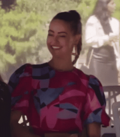 Woman In Pink And Blue Floral Top Smiling At Table GIF